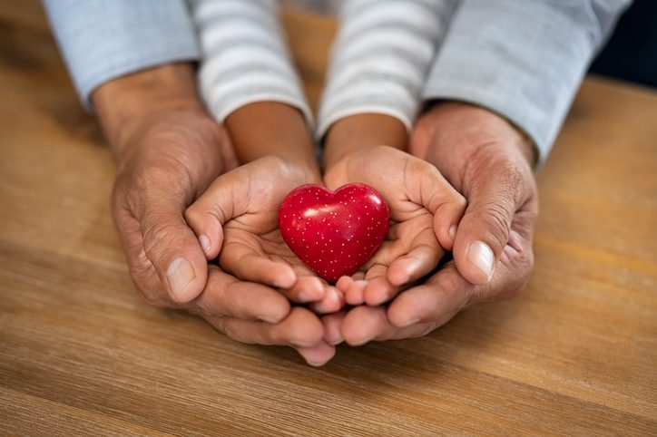 Man and child hand holding red heart