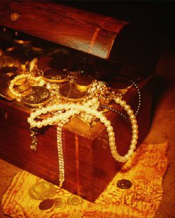 Treasure chest with pearls and gold inside on top of a treasure map